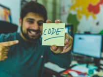 smiling man showing sticky note with code illustration