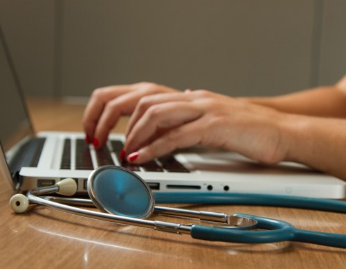 person sitting while using laptop computer and green stethoscope 