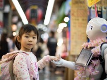 Photo of girl laying left hand on white digital robot