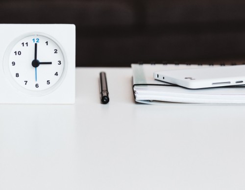 white desk clock near pen and book