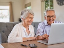Happy smiling retired couple using laptop at home