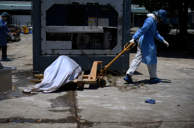 Health workers wearing protective gear bring a dead body past a refrigerated container outside of Teodoro Maldonado Carbo Hospital amid the spread of the coronavirus disease (COVID-19), in Guayaquil