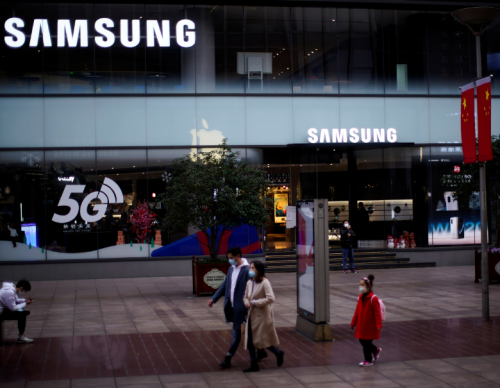 FILE PHOTO: People wears masks in front a Samsung Store at a main shopping area, in downtown Shanghai