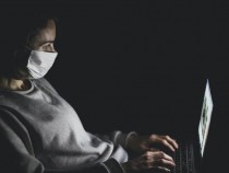 Person with mask using MacBook