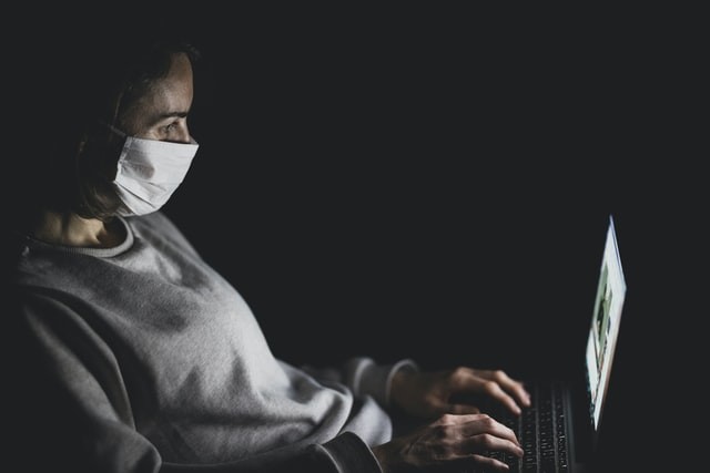 Woman with mask using MacBook